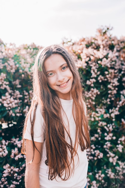 Foto gratuita niña sonriente con pelos largos mirando a cámara