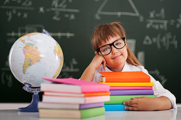 Niña sonriente con pila de libros