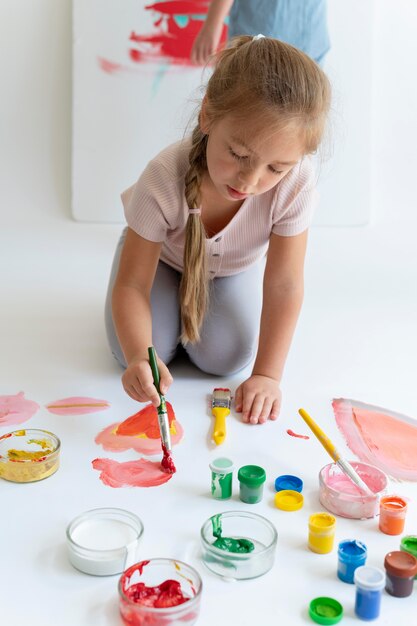 Niña sonriente pintando con pincel full shot