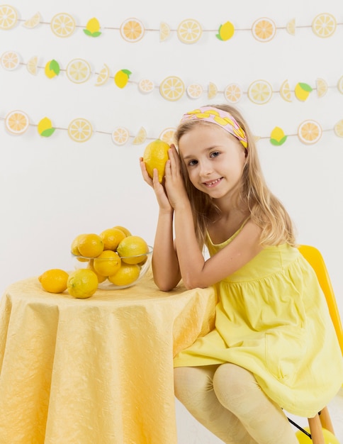 Niña sonriente posando con un limón