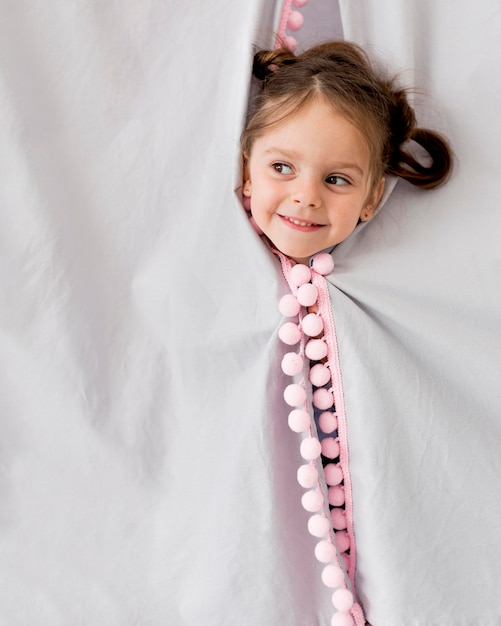 Foto gratuita niña sonriente posando mientras saca la cabeza de la tienda