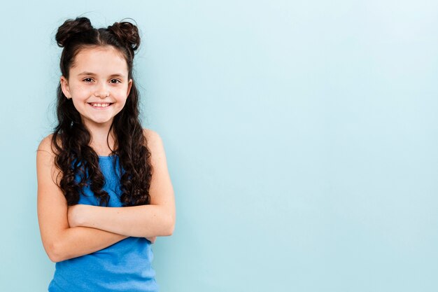 Niña sonriente posando sobre fondo azul