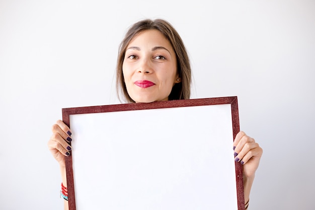 Niña sonriente de primer plano con un cartel o cartel blanco en blanco