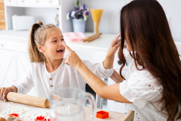 Niña sonriente que cocina con su madre