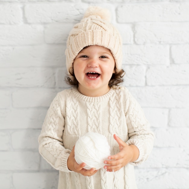 Niña sonriente que sostiene una bola de nieve