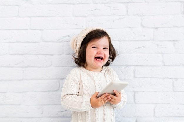 Foto gratuita niña sonriente que sostiene un teléfono