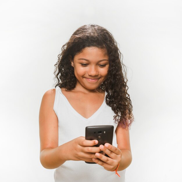 Niña sonriente que usa el teléfono móvil