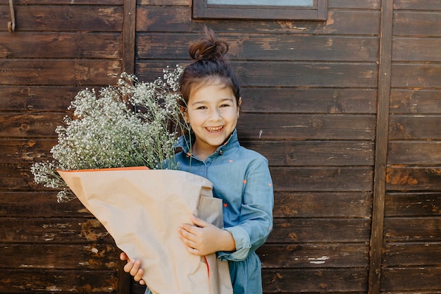 Niña sonriente con ramo de flores silvestres