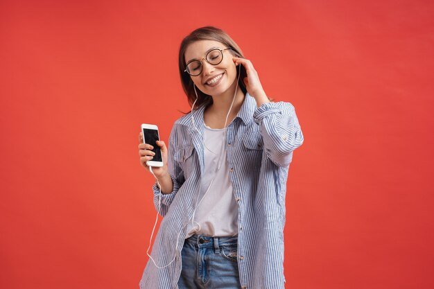 Niña sonriente en ropa casual y auriculares bailando moviendo las manos.