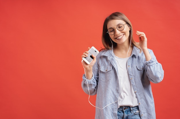 Niña sonriente en ropa casual y auriculares bailando moviendo las manos.