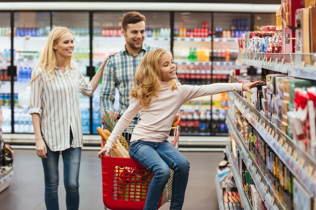 Niña sonriente sentada en un carrito de compras