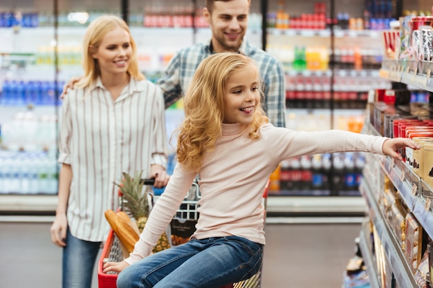 Niña sonriente sentada en un carrito de compras