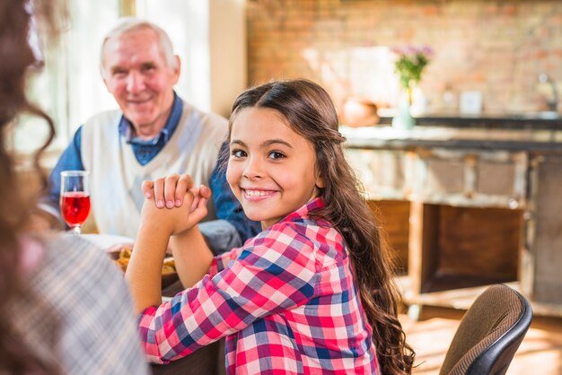 Niña sonriente sentada cerca de anciano