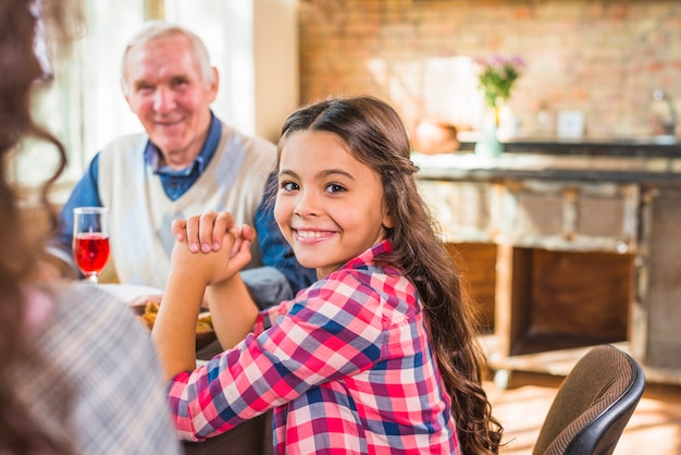 Niña sonriente sentada cerca de anciano