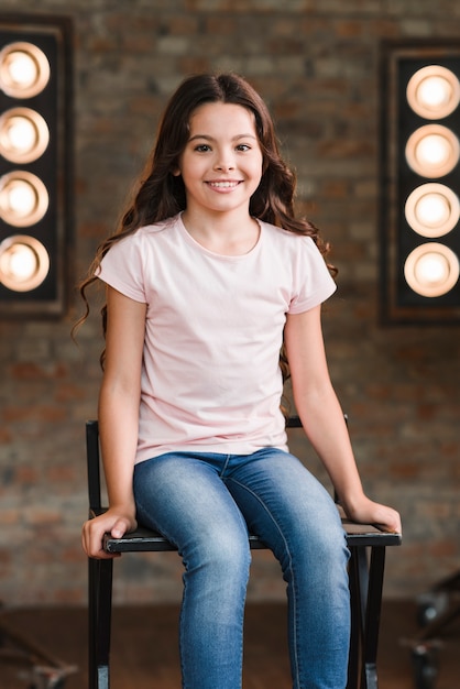 Niña sonriente sentada en la silla alta en el estudio