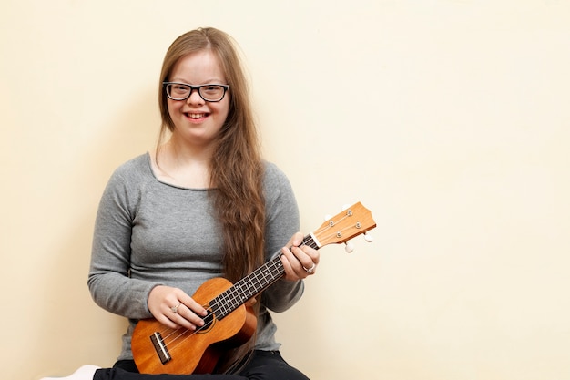 Niña sonriente con síndrome de down con guitarra