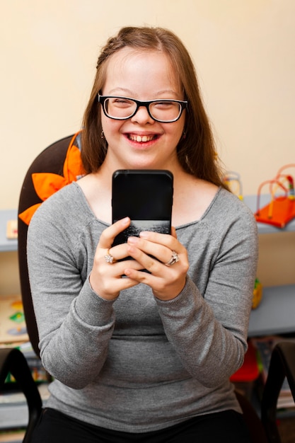 Foto gratuita niña sonriente con síndrome de down con teléfono