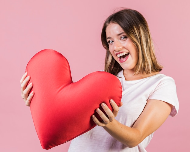 Niña sonriente sosteniendo una almohada en forma de corazón