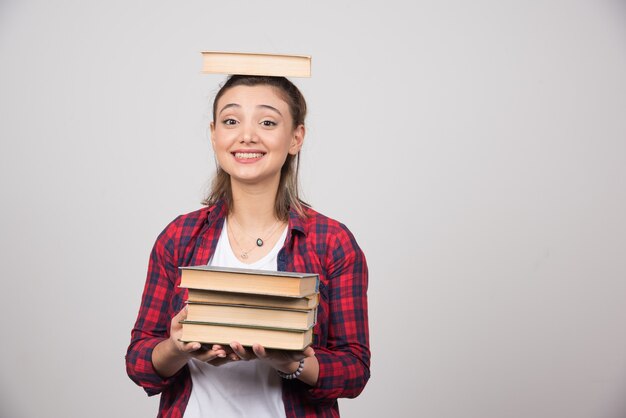 Una niña sonriente sosteniendo un libro sobre su cabeza.