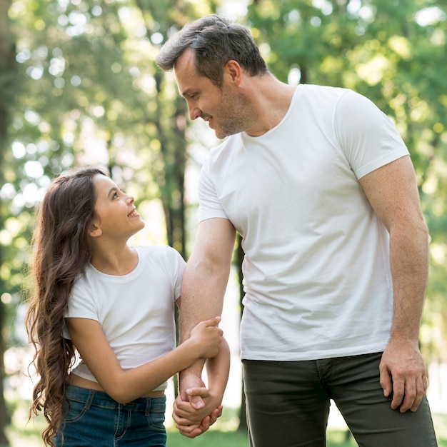 Niña sonriente sosteniendo la mano de su padre y mirándose