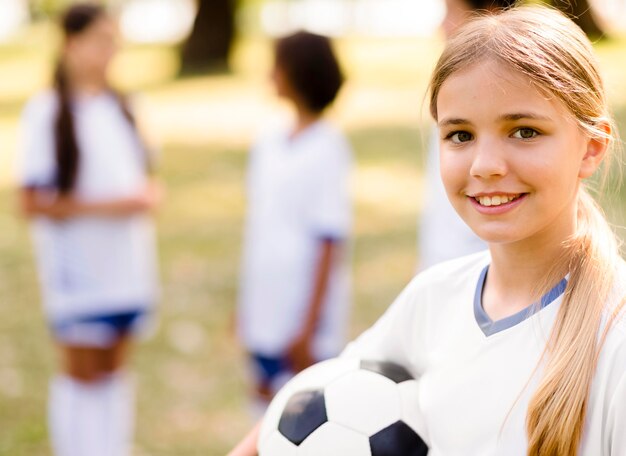 Niña sonriente sosteniendo una pelota de fútbol