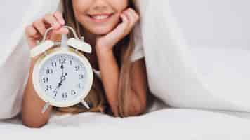 Foto gratuita niña sonriente sosteniendo un reloj blanco