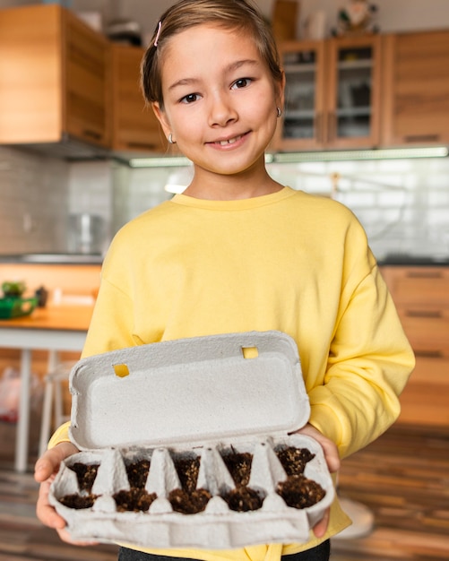 Foto gratuita niña sonriente sosteniendo semillas plantadas