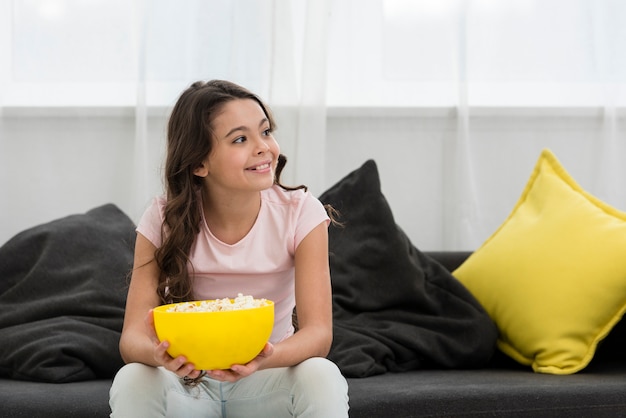 Foto gratuita niña sonriente sosteniendo un tazón de palomitas de maíz