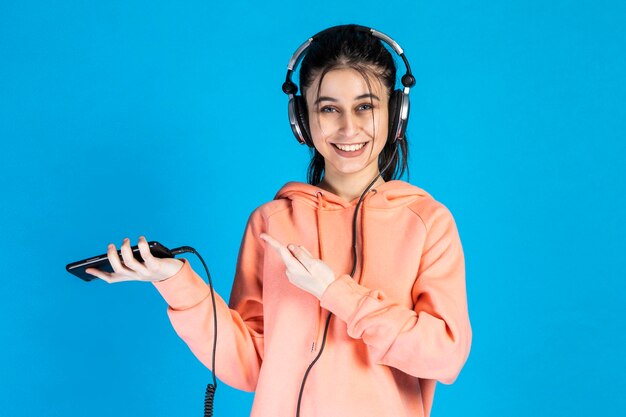 Niña sonriente sosteniendo el teléfono y usando audífonos