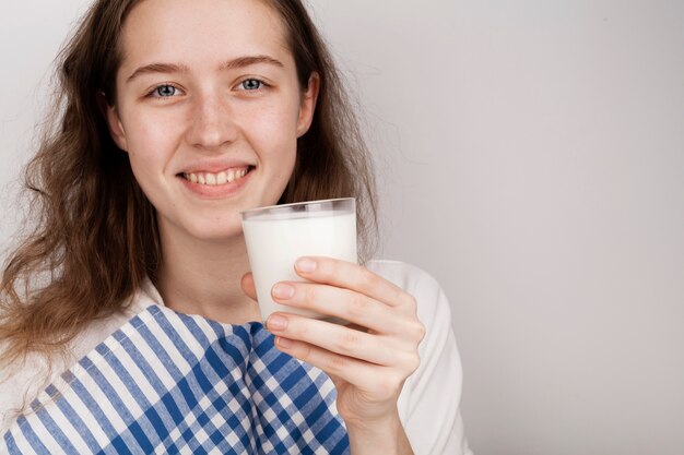 Niña sonriente sosteniendo un vaso de leche con espacio de copia