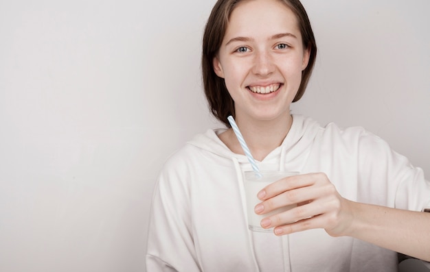 Niña sonriente sosteniendo un vaso de leche con espacio de copia