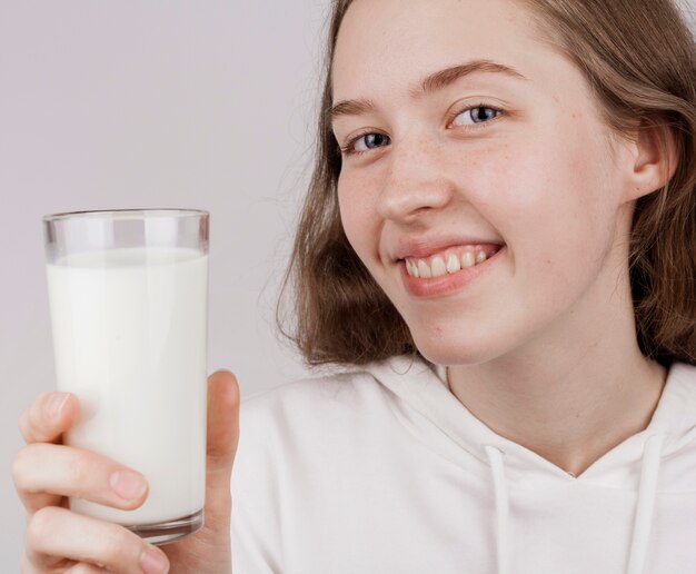 Niña sonriente sosteniendo un vaso de leche fresca