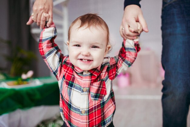 La niña sonriente sostiene las manos de los padres