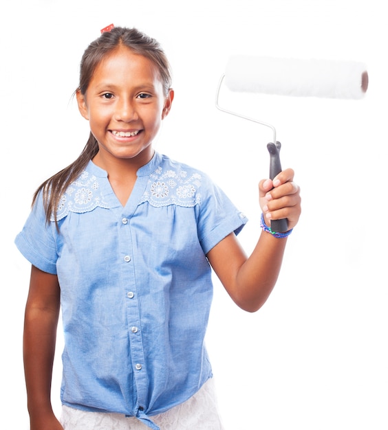 Niña sonriente sujetando un rodillo de pintura