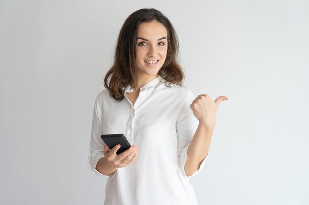 Niña sonriente con teléfono móvil que recomienda nueva aplicación, servicio, producto.