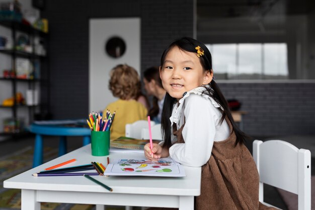 Niña sonriente de tiro medio con crayones