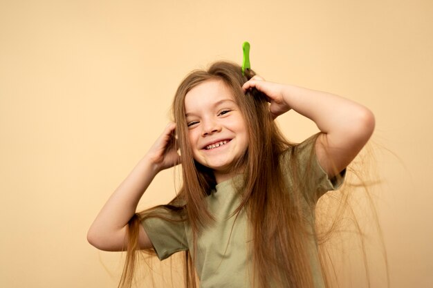 Niña sonriente de tiro medio con peine