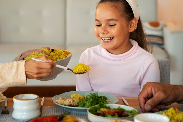 Foto gratuita niña sonriente de tiro medio sentada en la mesa