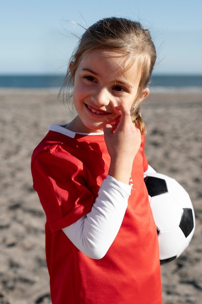 Niña sonriente de tiro medio sosteniendo pelota