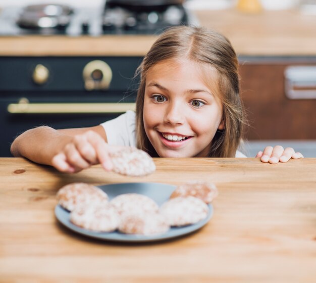 Niña sonriente tomando una deliciosa galleta