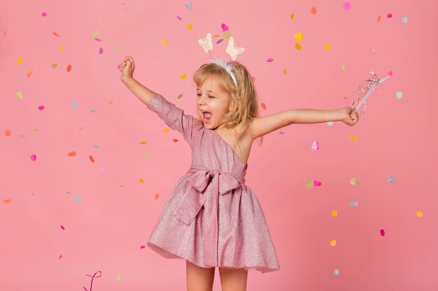 Niña sonriente en traje de hadas con confeti