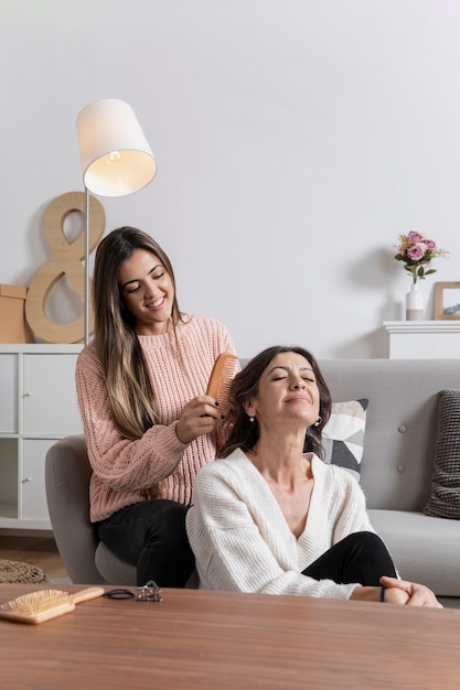 Niña sonriente trenzando el cabello de su madre