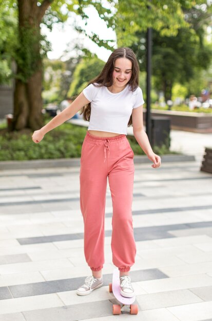 Niña sonriente usando su patineta afuera