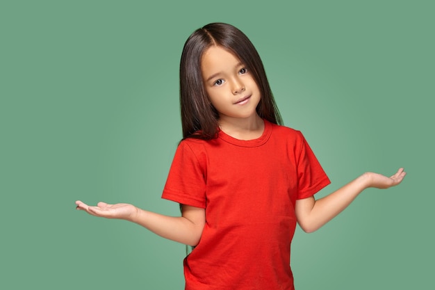 Niña sorprendida con los brazos extendidos aislada en el fondo verde