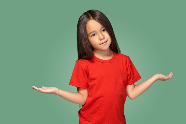 Niña sorprendida con los brazos extendidos aislada en el fondo verde