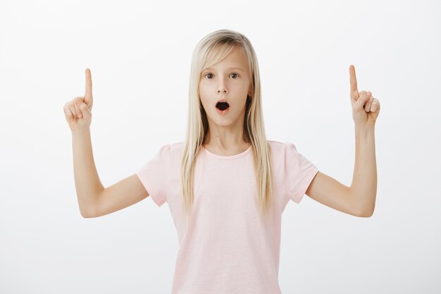 Niña sorprendida e impresionada apuntando hacia arriba