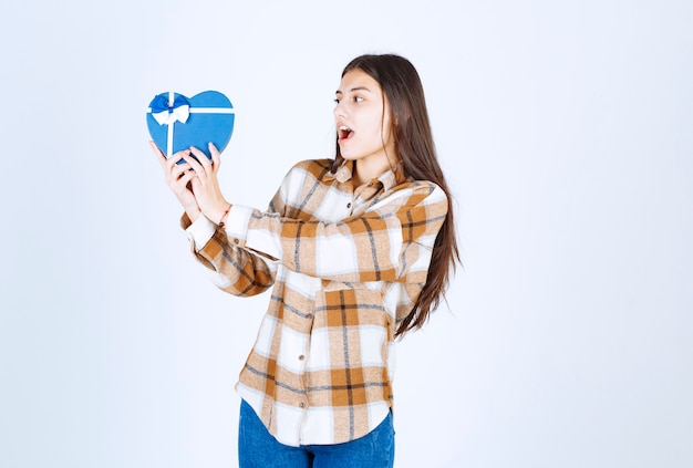 Foto gratuita niña sorprendida mirando regalo sorpresa en la pared blanca.