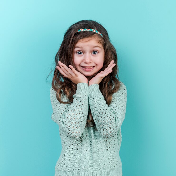 Foto gratuito niña sorprendida que se coloca en fondo azul