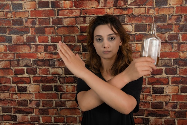 Niña sosteniendo alcohol y cruzó las manos. foto de alta calidad