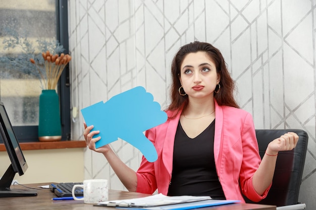 Niña sosteniendo una burbuja de idea azul en forma de pulgar hacia abajo y mirando hacia arriba